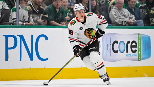 Connor Bedard handles the puck in a white Blackhawks jersey